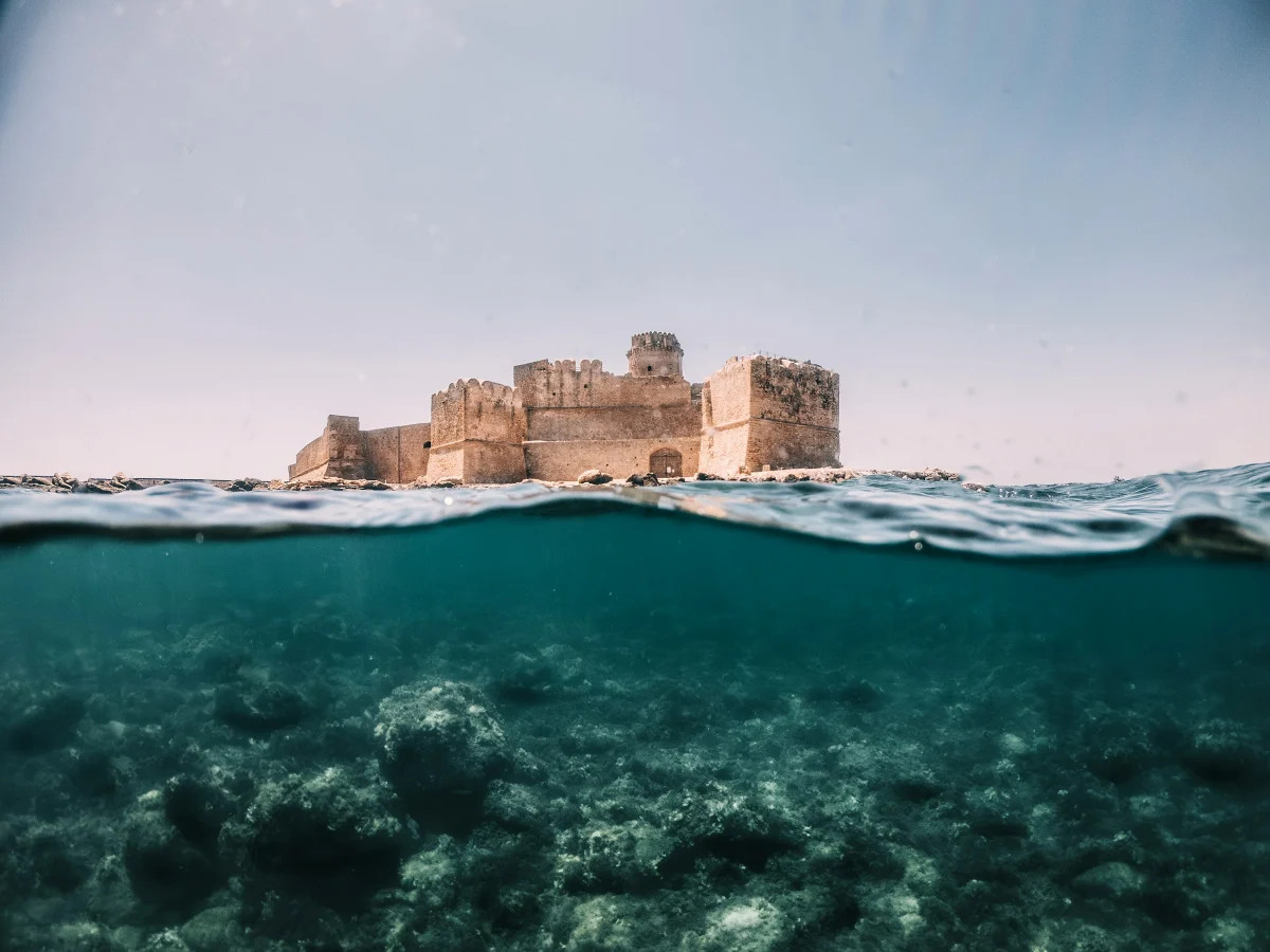 La fortezza aragonese di Le Castella vista dal mare, con la linea dell’acqua e il fondale in primo piano.
