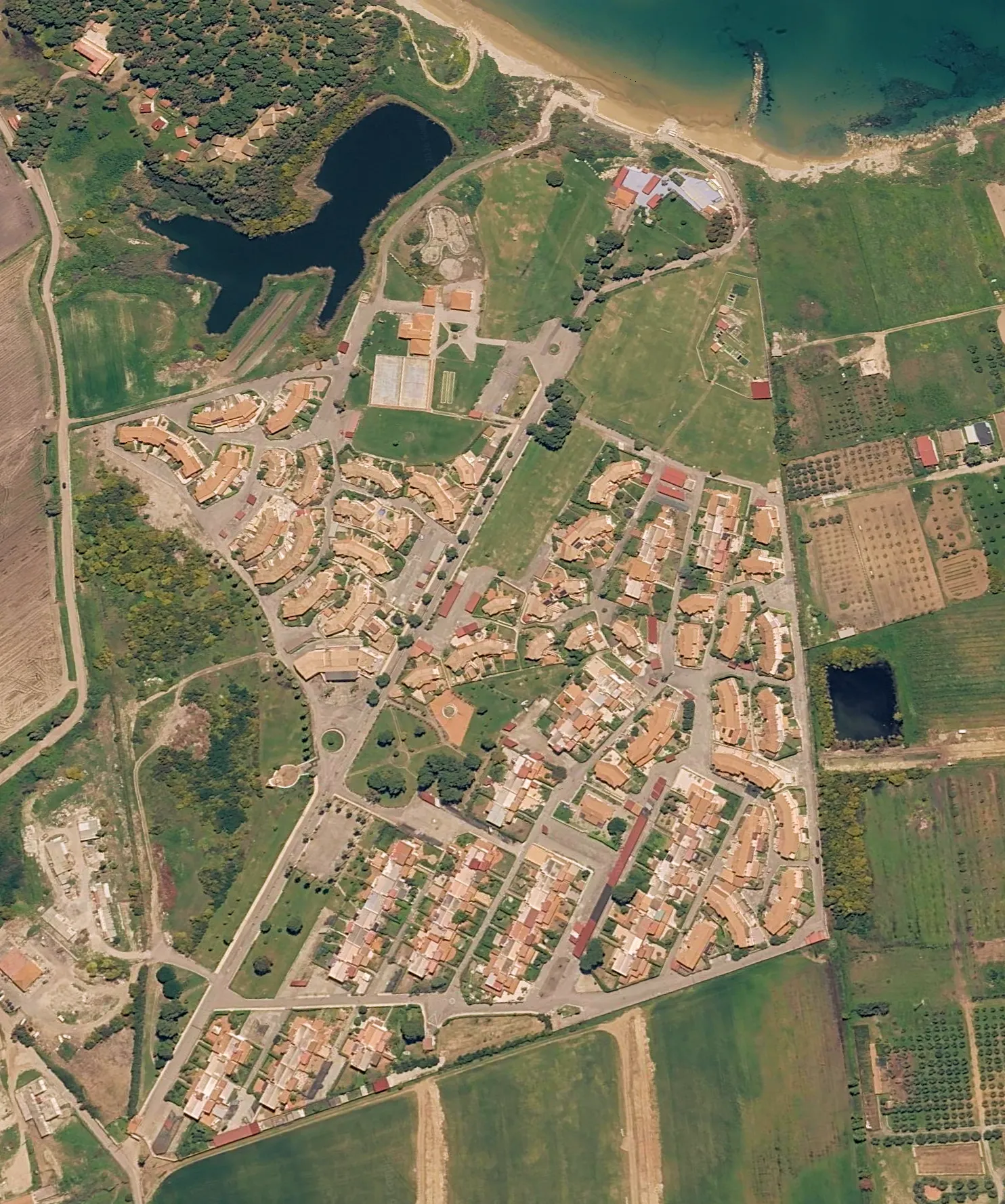 Vista aerea del Santa Cristina Village, con le case, gli spazi comuni, la spiaggia e il mare.
